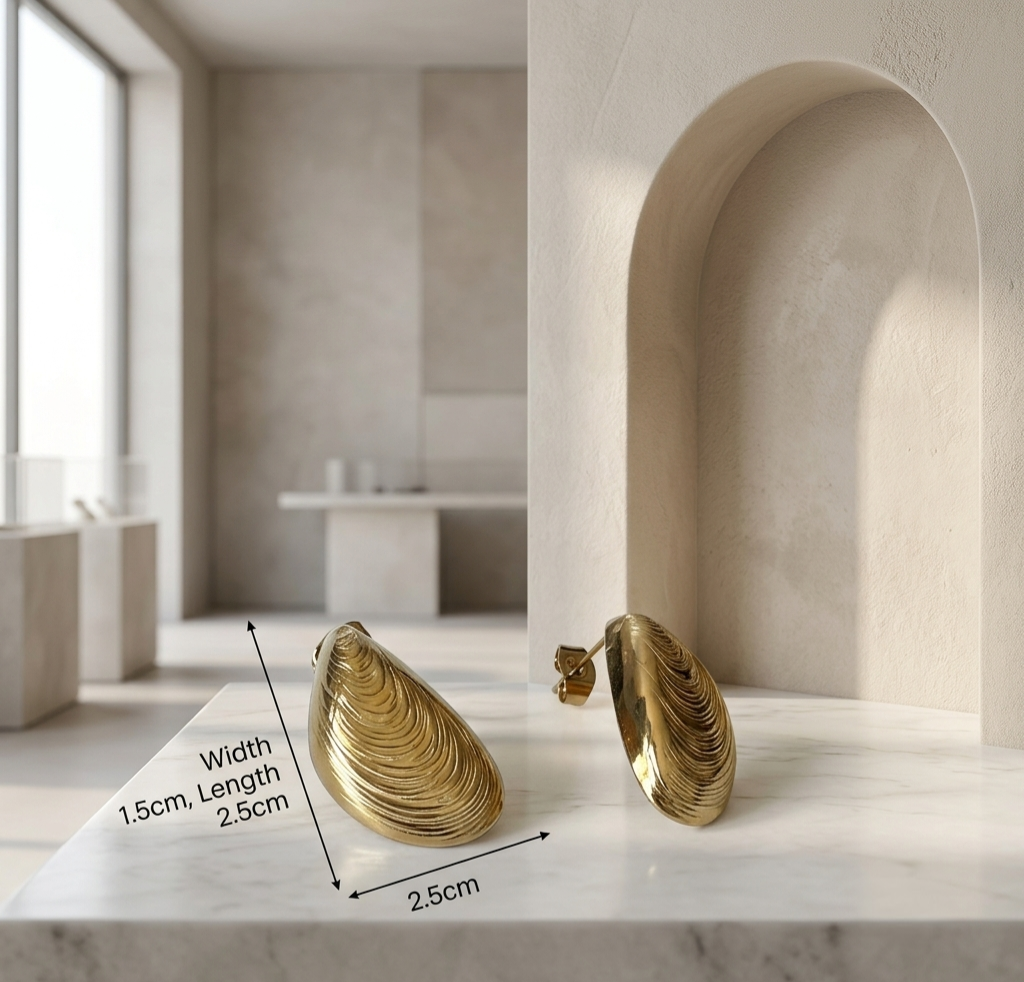 Gold hoop earrings on a marble surface with architectural background