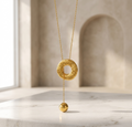 Gold necklace with a textured pendant on a marble surface